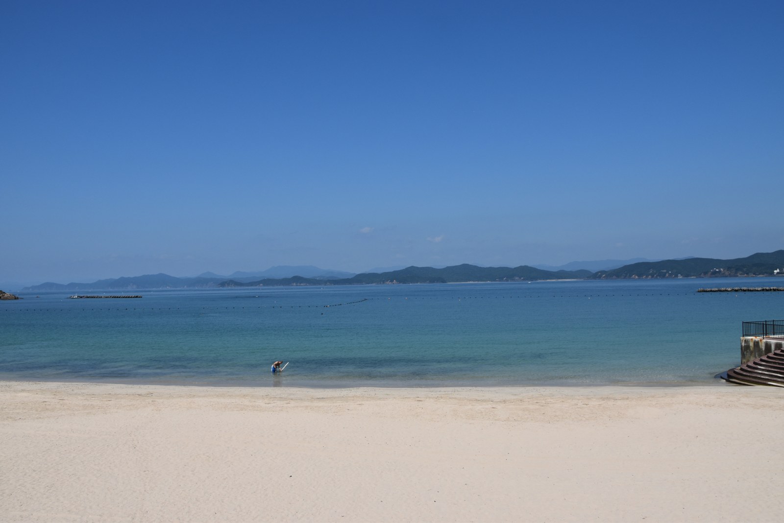 八月の砂浜。波打ちぎわに人がひとりだけ